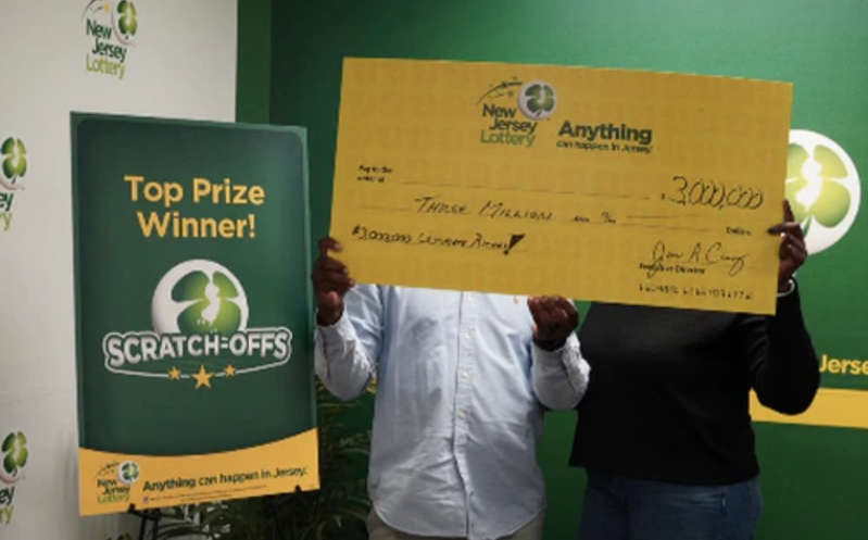 Ganador de la lotería en NJ tres veces un mismo día se esconde tras cheque simbólico de $3 millones en foto oficial